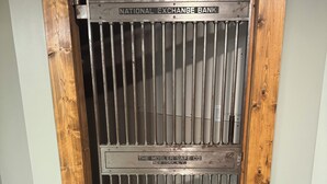 Une porte métallique portant les inscriptions « National Exchange Bank » et « The Mosler Safe Co. », un cadre en bois et un sol recouvert de moquette.