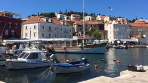 A marina with boats docked, buildings in the background, and a clear blue sky. - S&A Apartment (Sutivan)