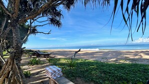 Une plage avec un banc en bois, des chaises longues et une pile de serviettes.