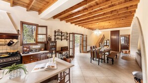 A spacious kitchen with wooden beams, a dining area, and a staircase leading to another level.