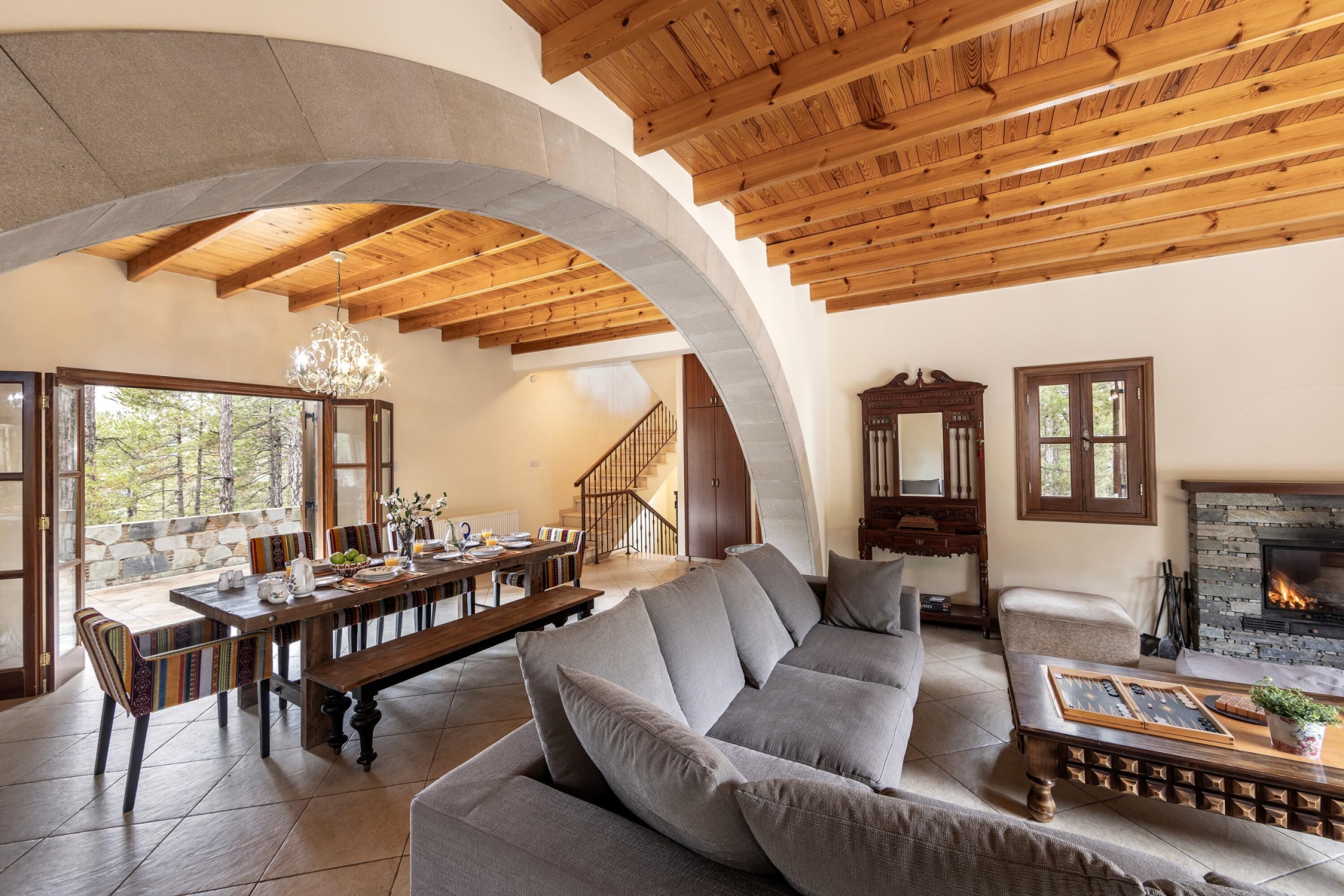 Un salón espacioso con techo de madera, chimenea y un revestimiento de piedra alrededor de la misma.