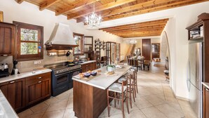 A spacious kitchen with wooden beams, a large island, and a dining area with a chandelier.
