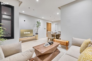 Relax in this stylish living room with a comfortable sofa, flat-screen TV, and dining area.