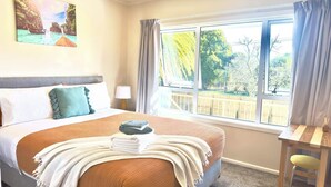 A hotel room with a large bed, a view of the outdoors, a desk, and a chair. - Steam land stay  (Rotorua)