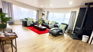 A modern living room with a sofa set, a coffee table, a red rug, and a fireplace. - Steam land stay  (Rotorua)