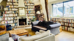 A cozy living room with a fireplace, a sofa, a coffee table, and a bookshelf filled with books. - Charming flat under the roof (Paris)