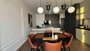 A modern dining area with a black table, four orange chairs, and hanging pendant lights. - Joy City Stay Nord One N2-49 (Timișoara)