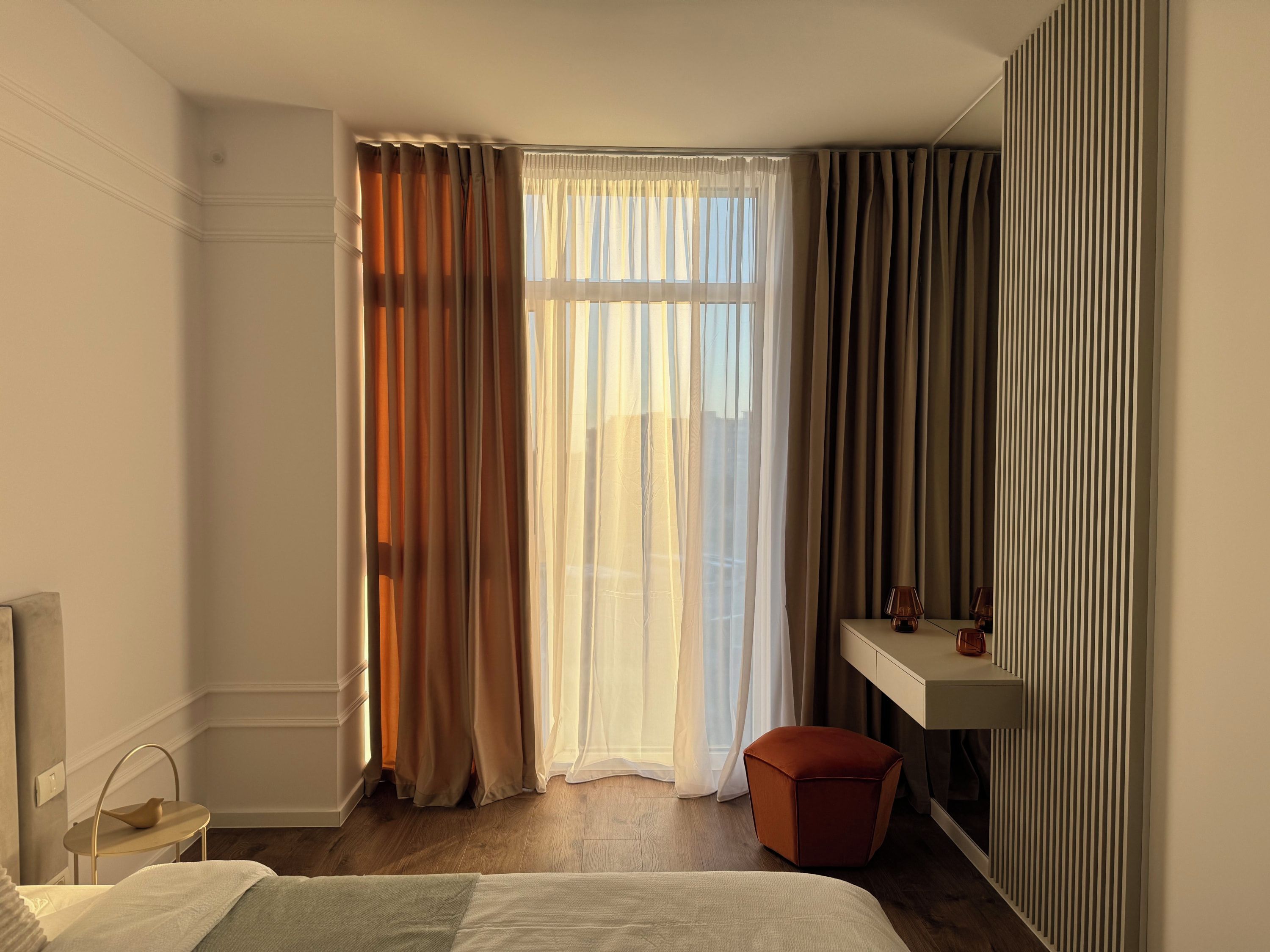 Une chambre d’hôtel avec un lit, une table de chevet, une lampe, une fenêtre avec des rideaux et un radiateur.
