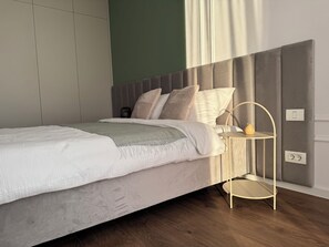 A modern bedroom with a bed, bedside table, and a wall-mounted light fixture. - Joy City Stay Nord One N2-49 (Timișoara)