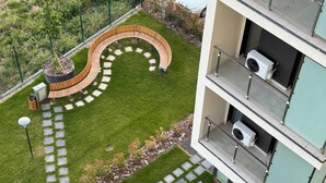 A modern building with a curved outdoor seating area, a well-maintained lawn, and a clear pathway. - Joy City Stay Nord One N2-49 (Timișoara)