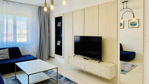 Una sala de estar moderna con una televisión de pantalla plana, un sofá, una mesa de centro y un mueble para la televisión.