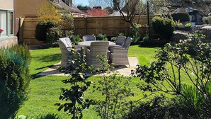 A residential backyard with a patio area, outdoor furniture, and a wooden fence. - Meadow Rise (Cheltenham)