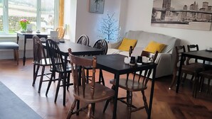 A dining area with a table and chairs, a sofa, and a cityscape painting on the wall. - Meadow Rise (Cheltenham)