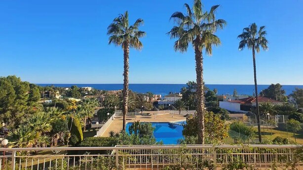 A pool area with palm trees and a view of the sea. - Apartamento 2 Habitaciones Aguilas Junto al mar (Águilas)