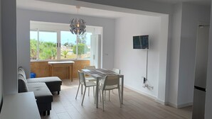 A modern kitchen with a dining area, large windows, and a flat-screen TV mounted on the wall. - Apartamento 2 Habitaciones Aguilas Junto al mar (Águilas)