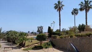 A park with palm trees, a playground, and a swimming pool. - Apartamento 2 Habitaciones Aguilas Junto al mar (Águilas)