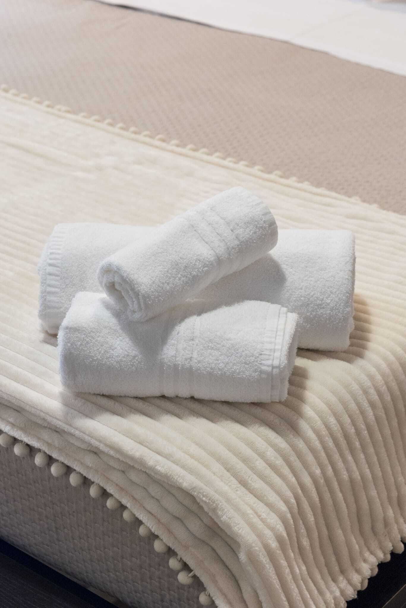 A stack of white towels on a textured bedspread.
