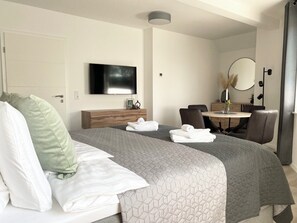 Ein Hotelzimmer mit Bett, Schreibtisch, Stuhl, Fernseher und Spiegel.