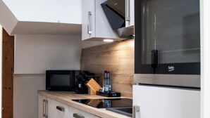 A modern kitchen with white cabinetry, a wooden countertop, a microwave, and a built-in oven.