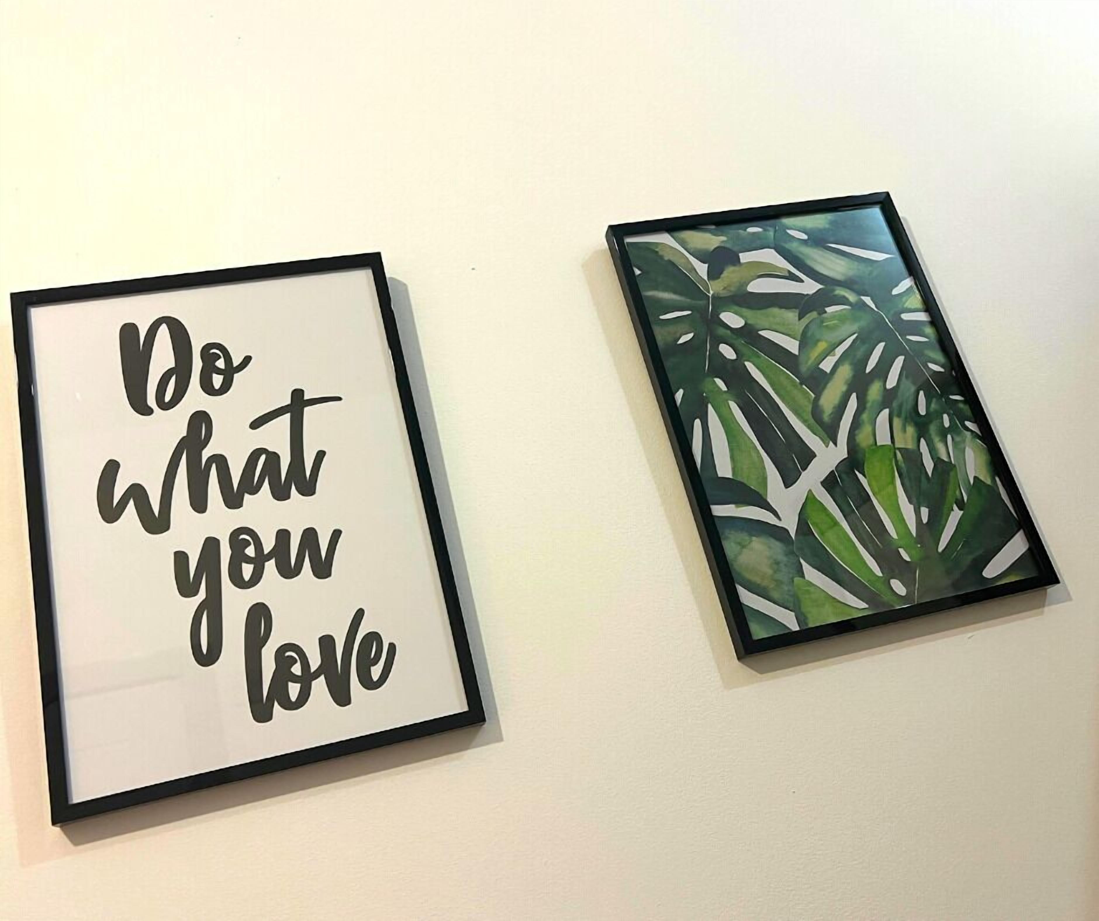 Two framed pictures on a wall; one says "Do What You Love" and the other features green leaves.