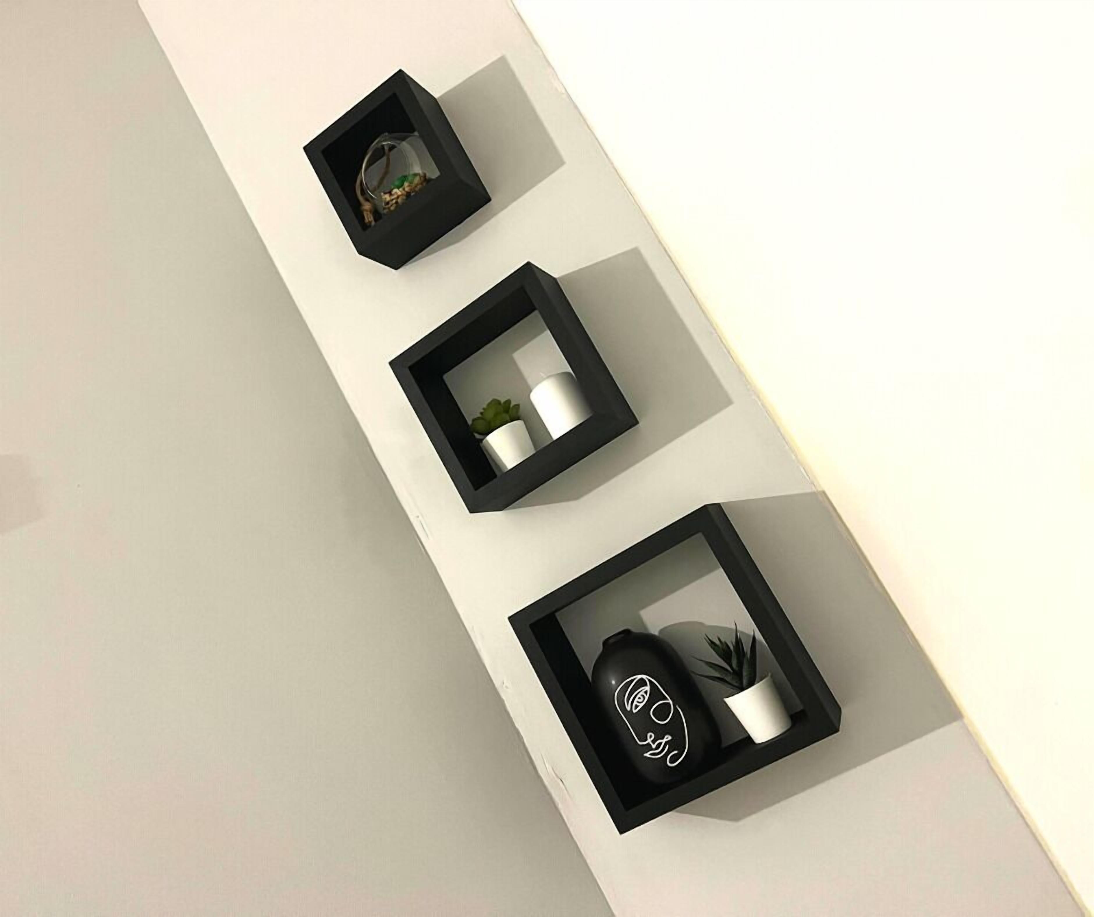 Três prateleiras de parede com moldura preta e diversos objetos decorativos.