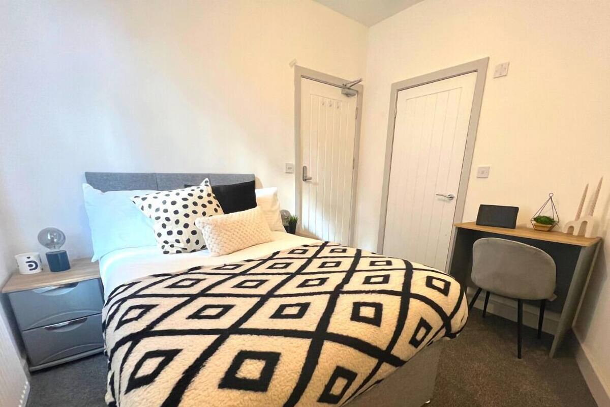 A bedroom with a bed, a desk, and a chair.