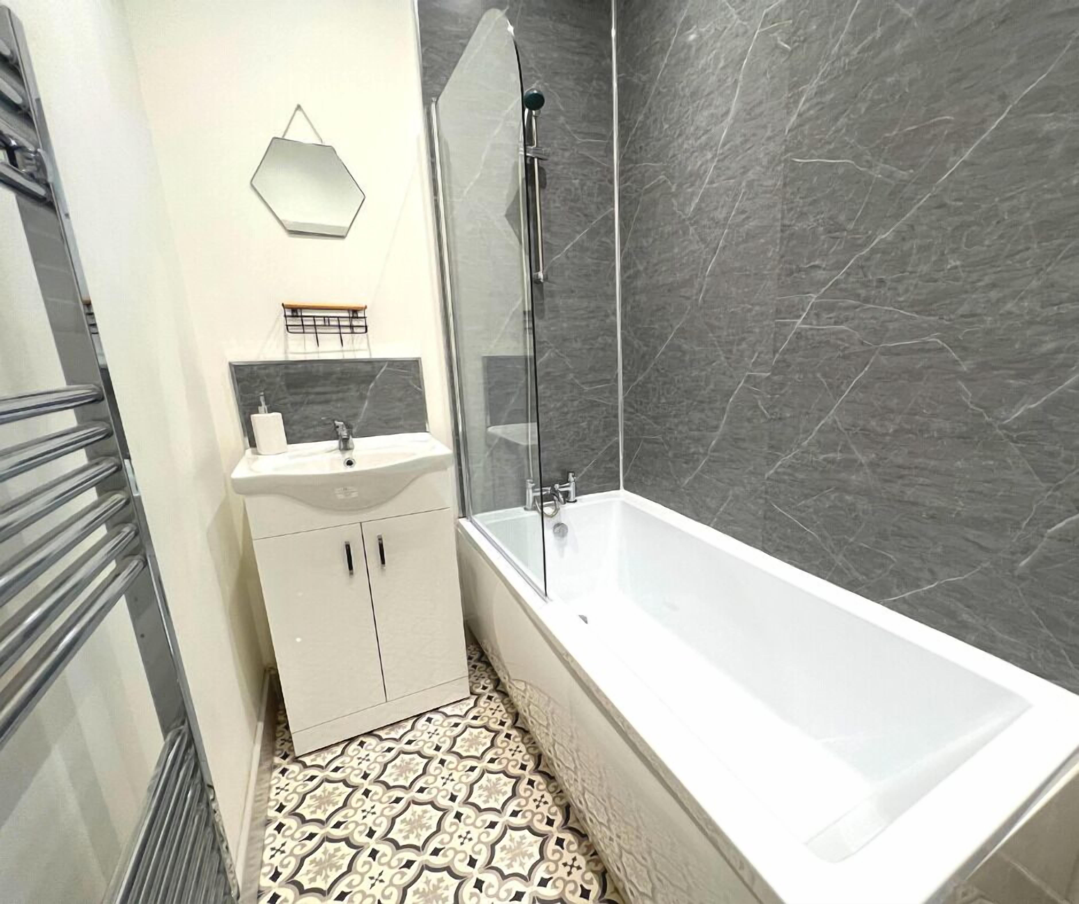 A bathroom with a white bathtub, a sink with a mirror above it, and a shower area.