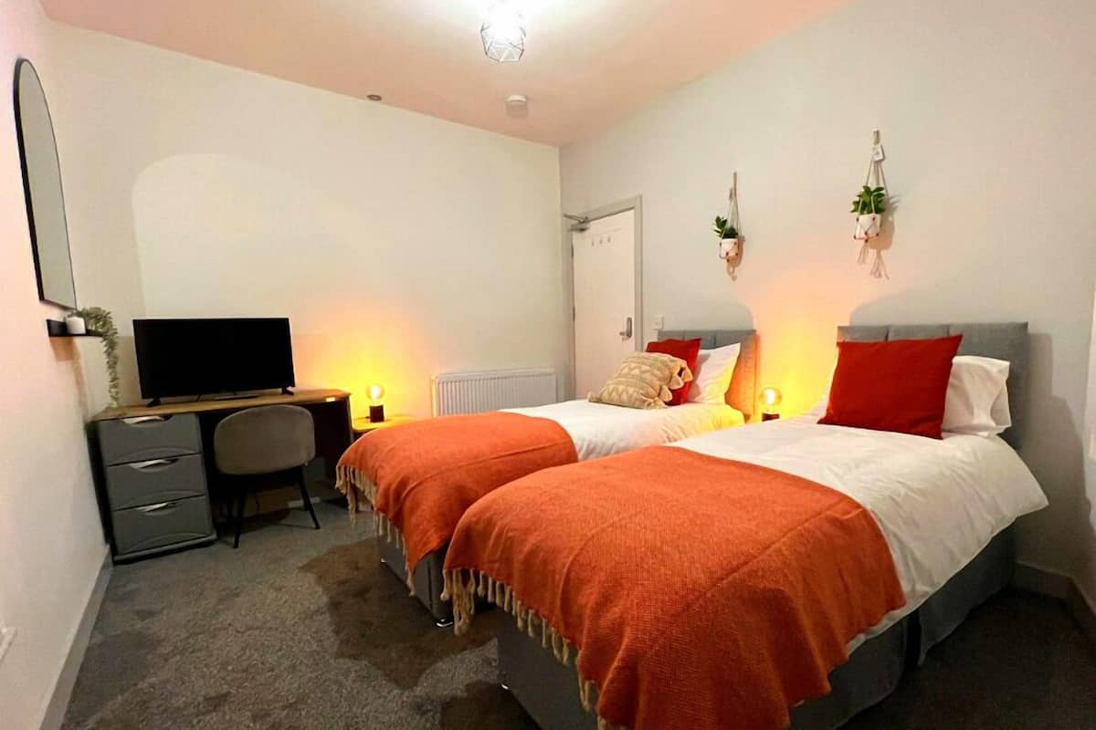 A bedroom with two beds, a desk, a chair, and a TV.
