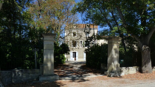 Un sendero conduce a un edificio de estilo arquitectónico tradicional, flanqueado por pilares de piedra y rodeado de árboles.