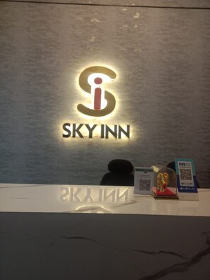 Ein SKYNN Hotels Schild mit einem QR-Code und einer Zahlungskarte auf einer Theke.