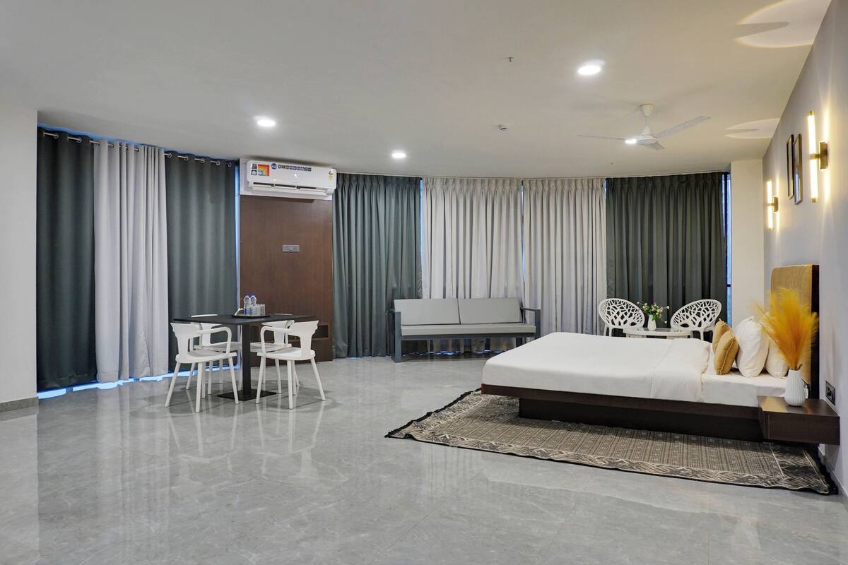 A modern hotel room with a bed, a desk, and a seating area.