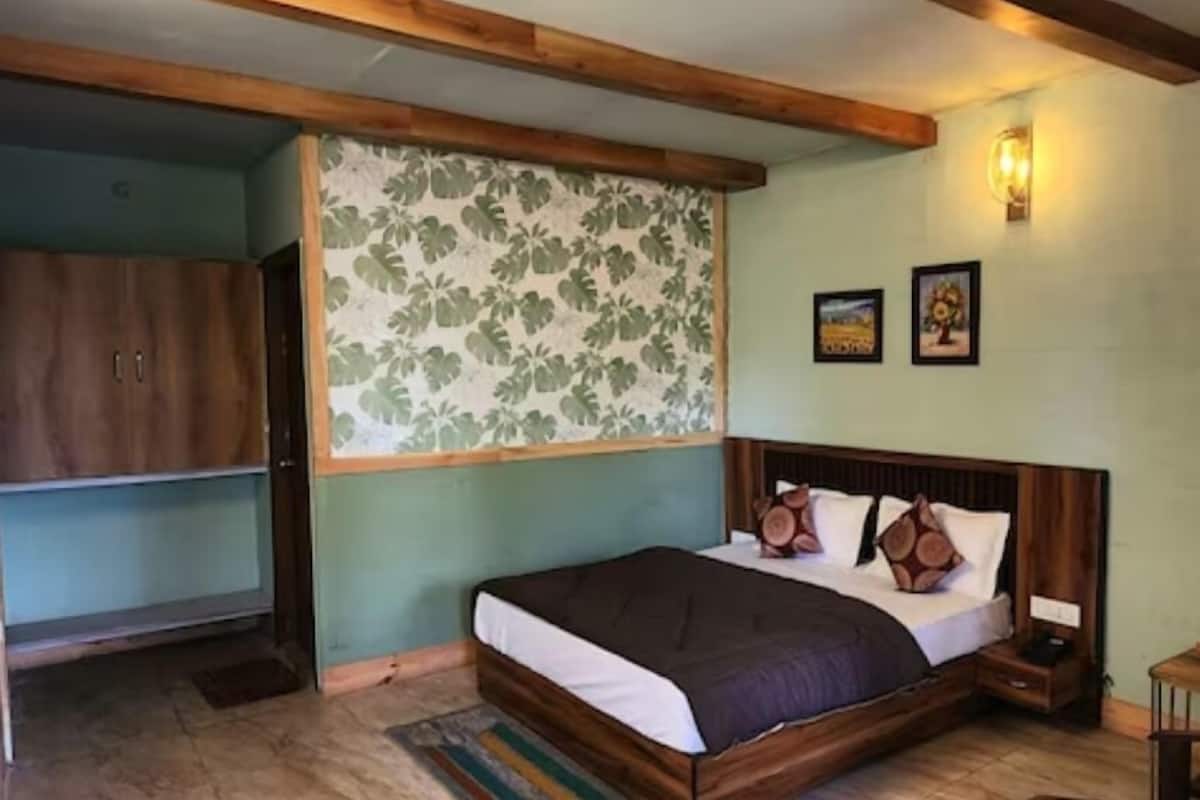 A bedroom with a wooden bed, a nightstand, a wardrobe, and a floral-patterned wall.