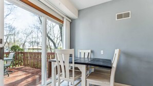 A dining area with a table and chairs, a sliding glass door leading to a deck, and a gray wall.