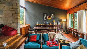A cozy living room with a stone wall, wooden ceiling, and large windows.
