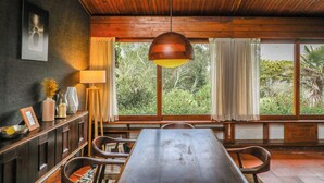 A dining area with a wooden ceiling, a table, chairs, and a hanging pendant light.