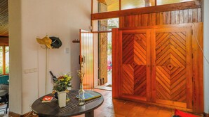 A wooden door with a chevron pattern, a round table with a vase of flowers, and a wall-mounted hat rack.