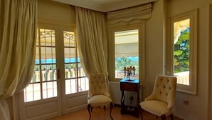 Une pièce spacieuse avec deux fauteuils, une table basse en verre et de grandes fenêtres dotées de rideaux.