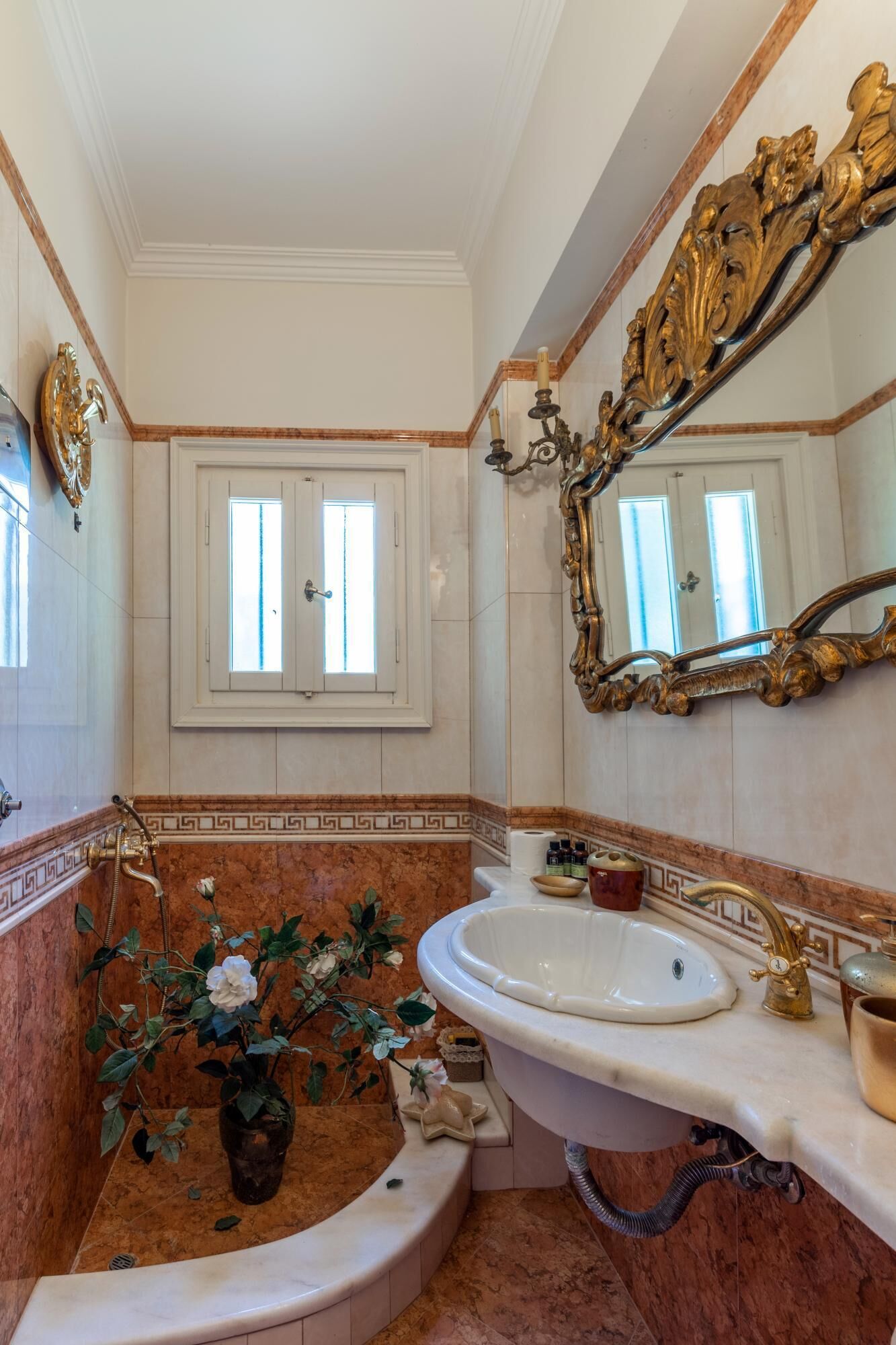 A bathroom with a marble sink, a bathtub, and a large ornate mirror.