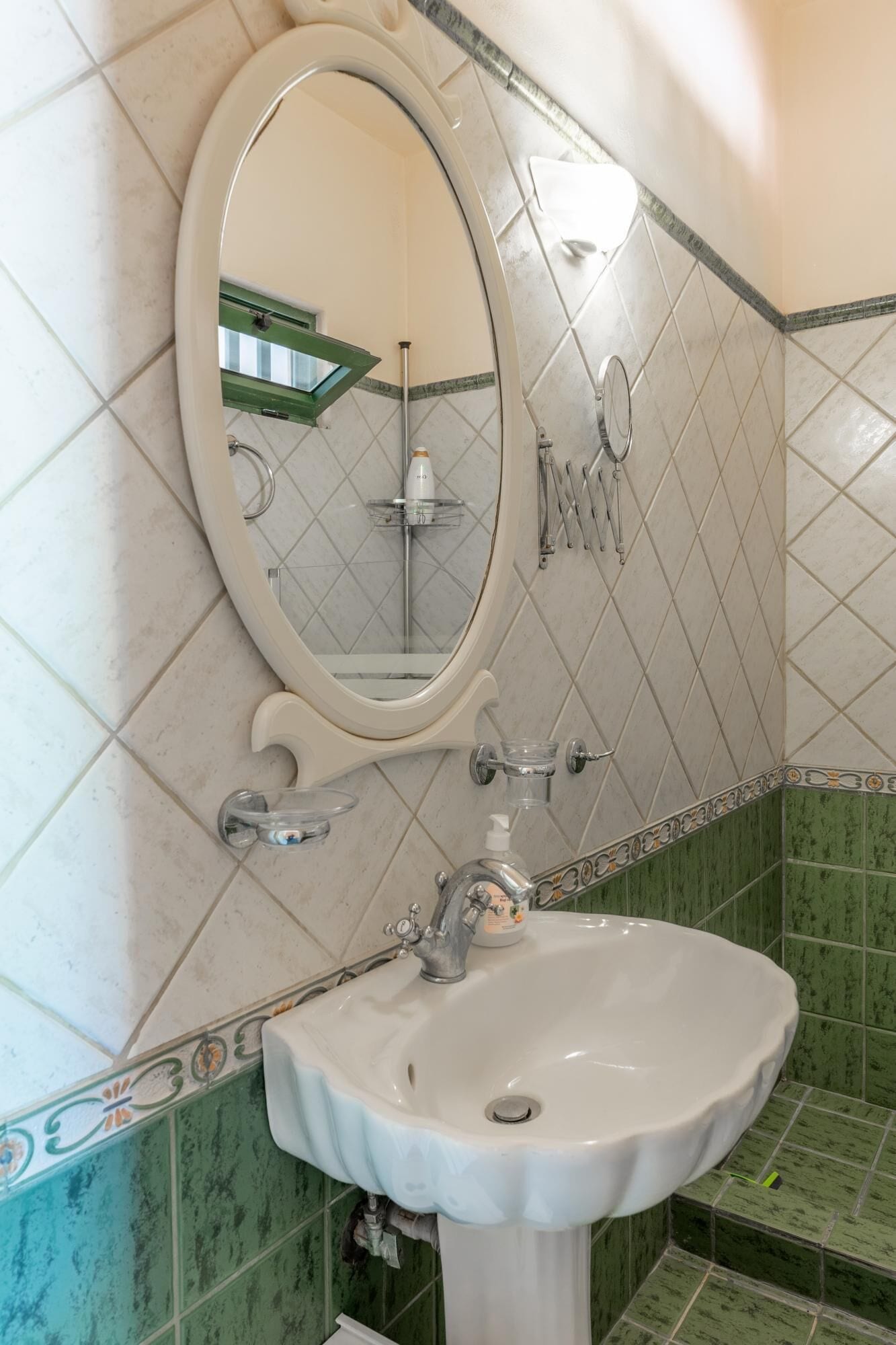 A bathroom with a white sink, a mirror, and green-tiled walls.