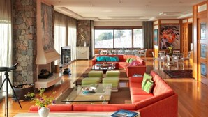 A spacious living room with a stone wall, a fireplace, a large sofa set, and a dining area with a table and chairs.