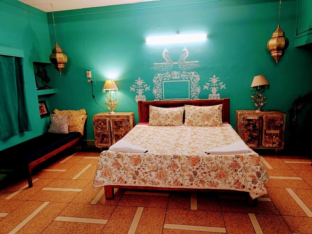 A bedroom with a bed, two nightstands, a bench, and a wall with decorative elements.