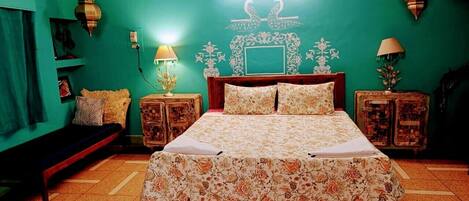 A bedroom with a bed, two nightstands, a bench, and a wall with decorative elements.