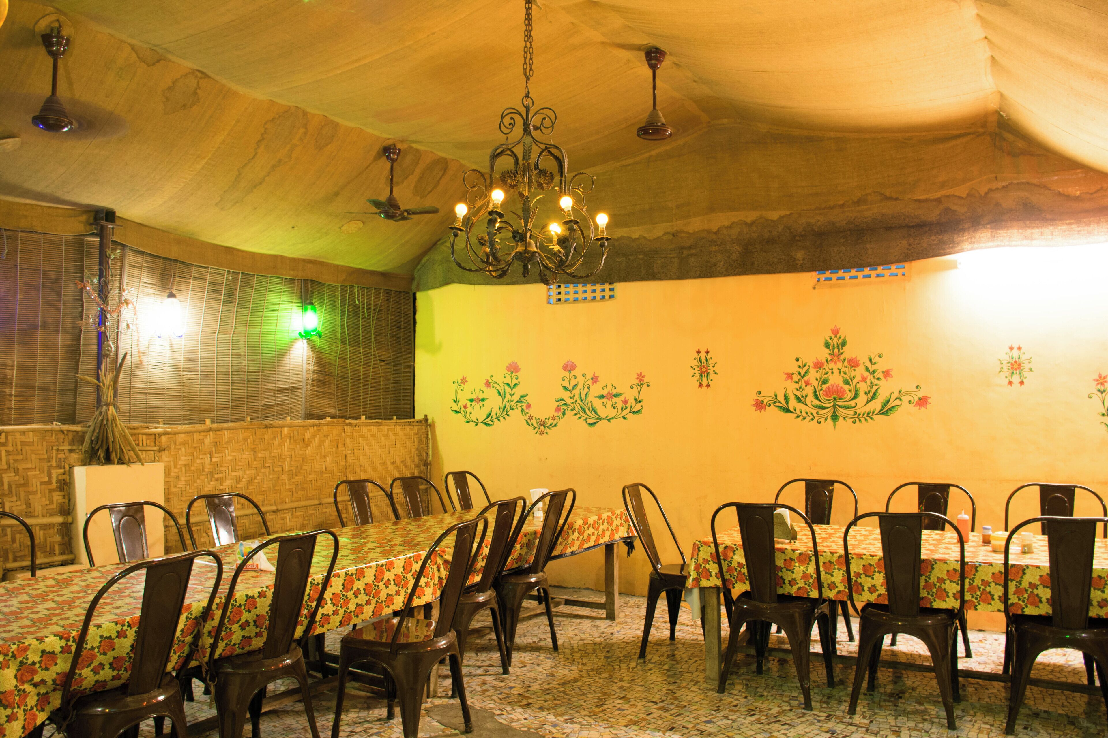 A dining area with a long table and chairs, a chandelier, and decorative wall art.