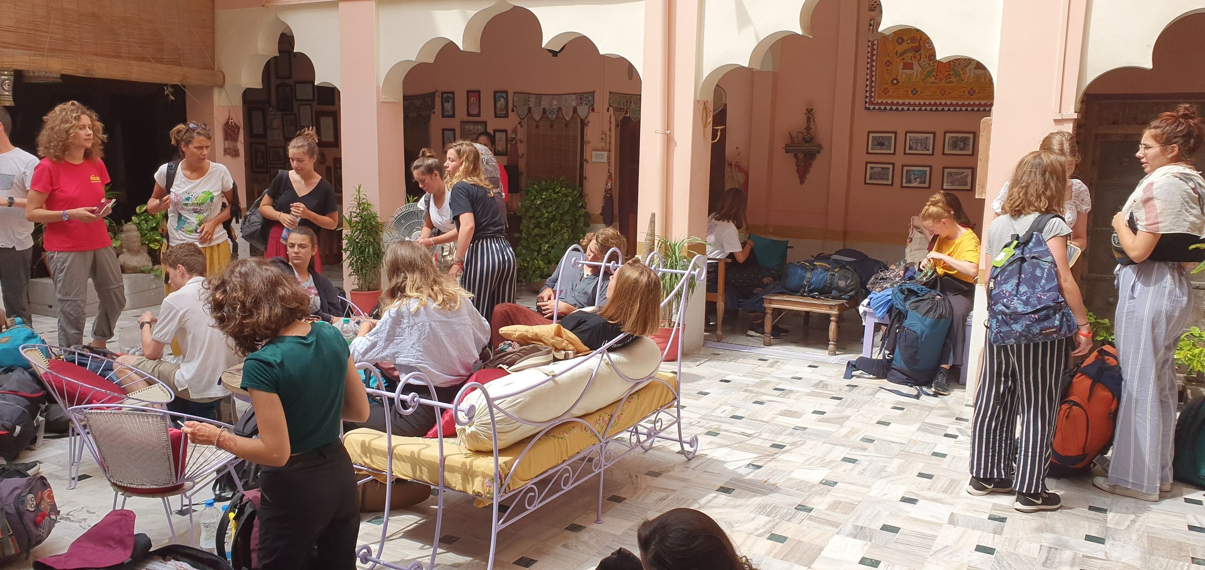 A courtyard with a bed, chairs, and people.