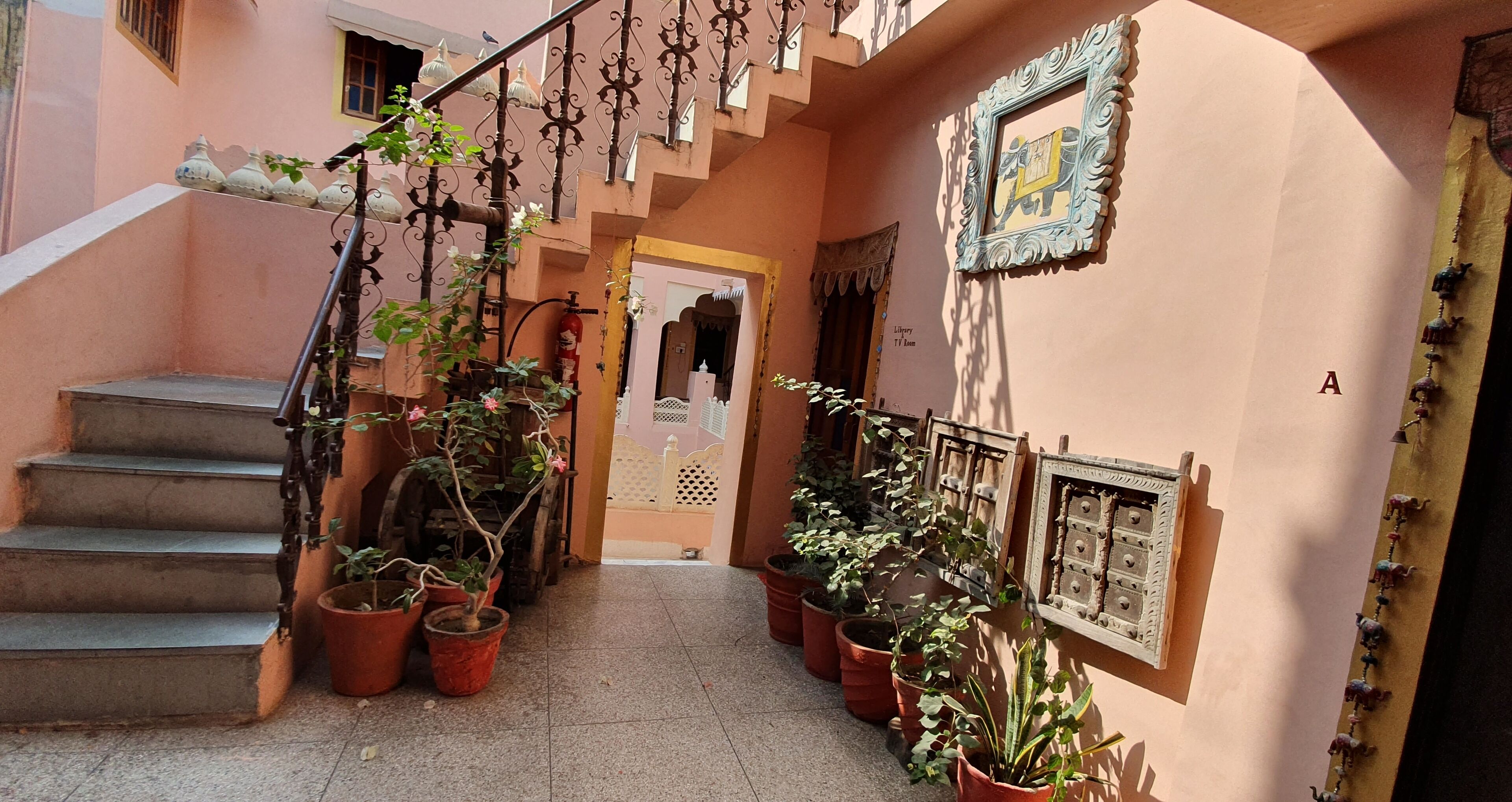 Un escalier orné de plantes en pot, un extincteur et une porte portant l’inscription « Bibliothèque ».