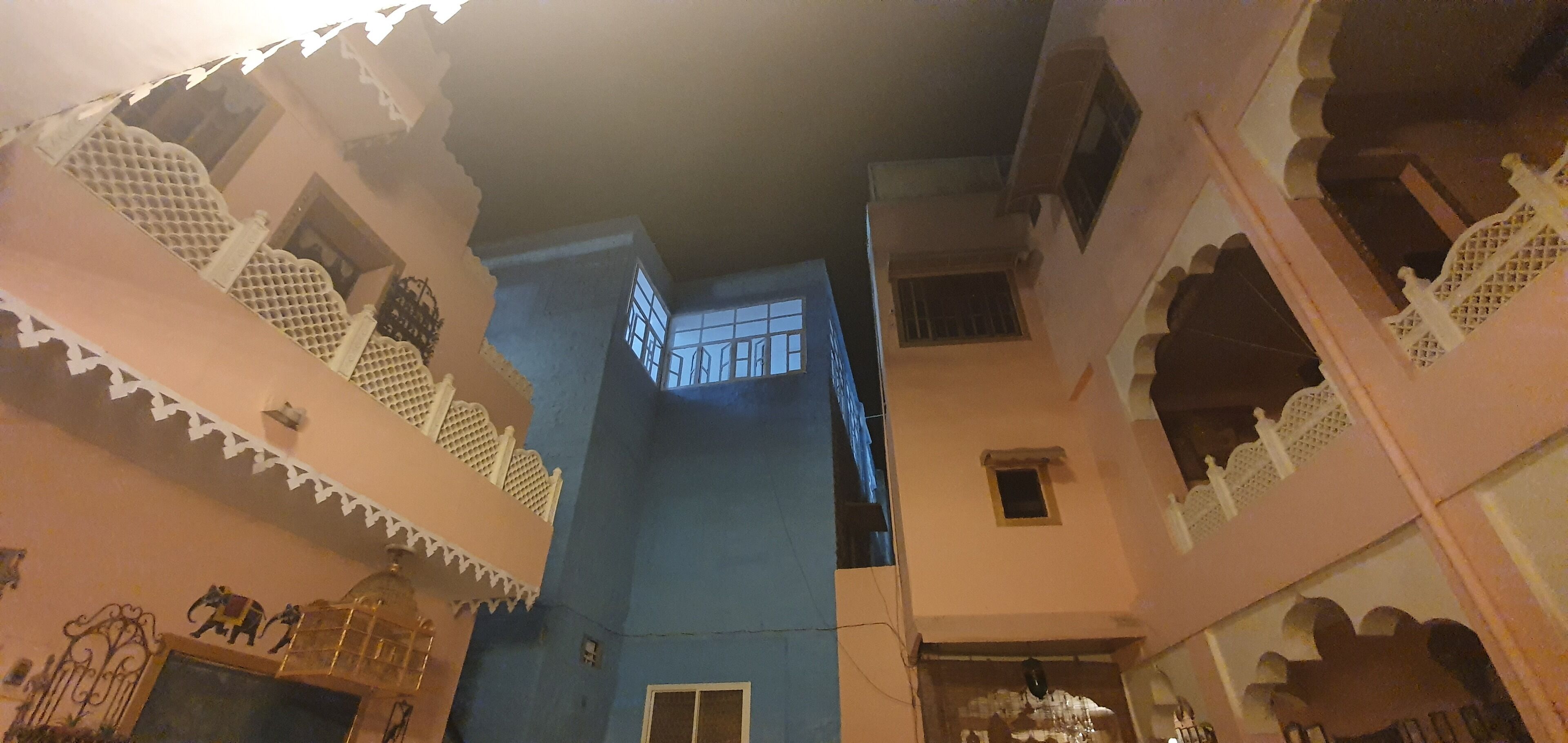 A narrow corridor with traditional architectural elements, including ornate balconies and a blue wall.