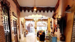 A hallway with patterned flooring, a chandelier, and a door with intricate designs. - Durag Niwas (Jodhpur)