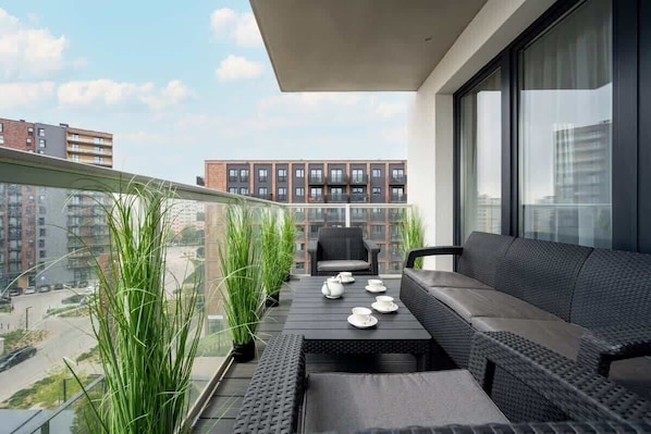 Un balcon avec un canapé, une table et des plantes en pot.
