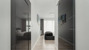 Een hal met een bed, een slaapbank en een muur met ingelijste foto's.