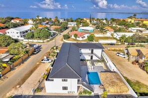 Une maison moderne à deux étages avec piscine, située dans un quartier résidentiel en bord de mer, offrant une vue dégagée sur l’océan.